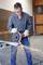 A person is cutting through a metal pipe with an angle grinder in a workshop, sparks flying. Wearing safety glasses and gloves.