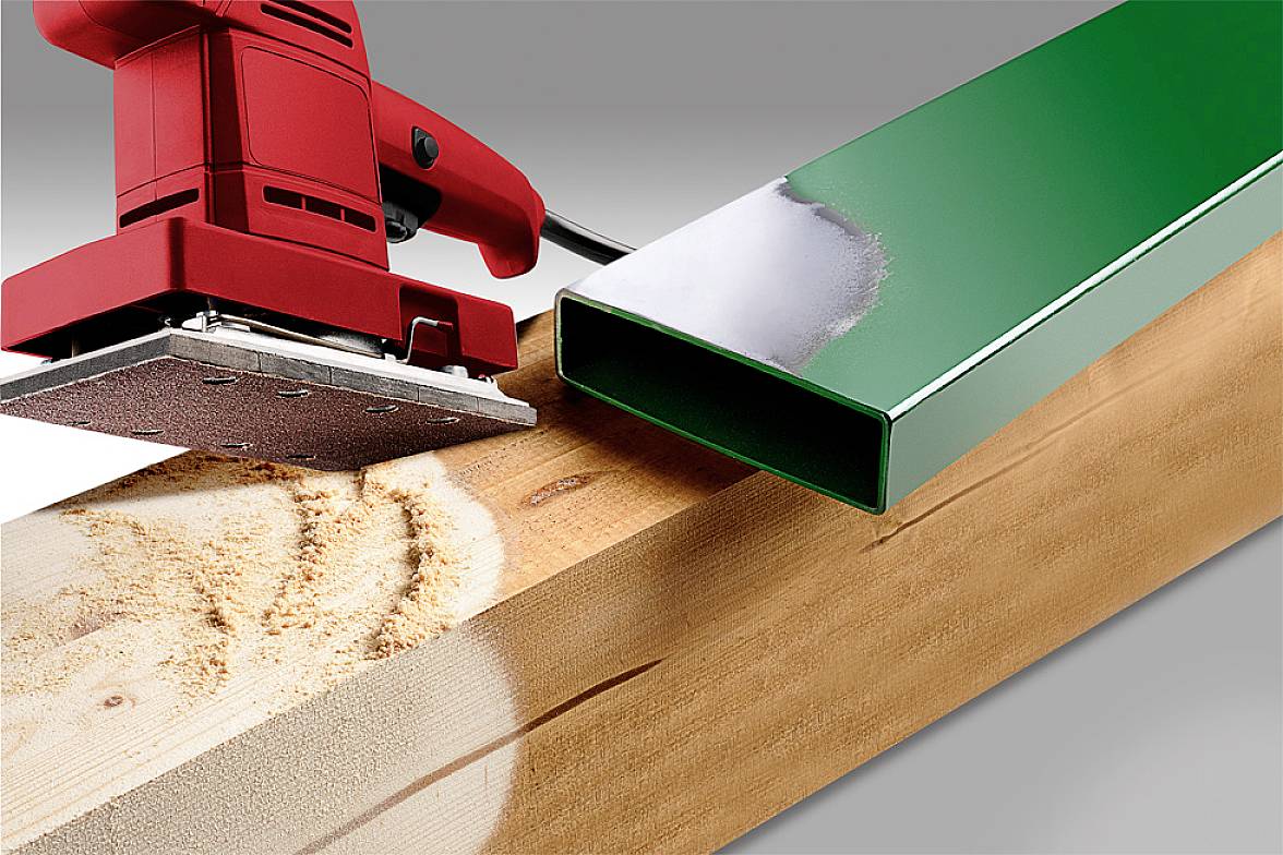 'Close-up of a red grinding machine sanding a wooden beam. Next to it, a green metal box for comparison.'