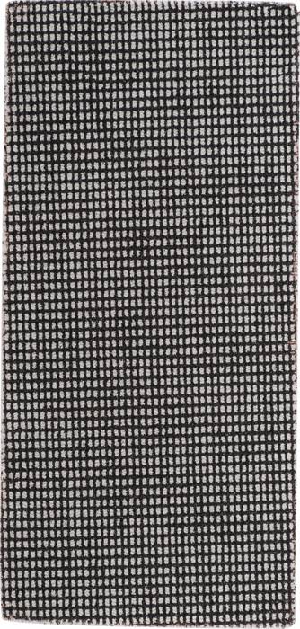 A rectangular rug with a black and cream tile pattern, creating geometric and symmetrical forms.
