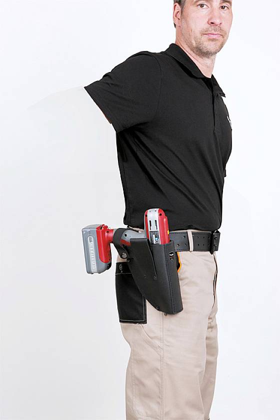 A man in workwear is wearing a tool belt with tools. He is standing sideways and looking towards the camera.