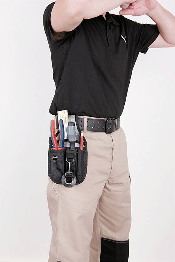 Person wearing a black polo shirt and beige trousers with a tool belt full of tools around their waist.