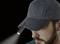 A man wearing a dark baseball cap with a small torch attached, shining forward.