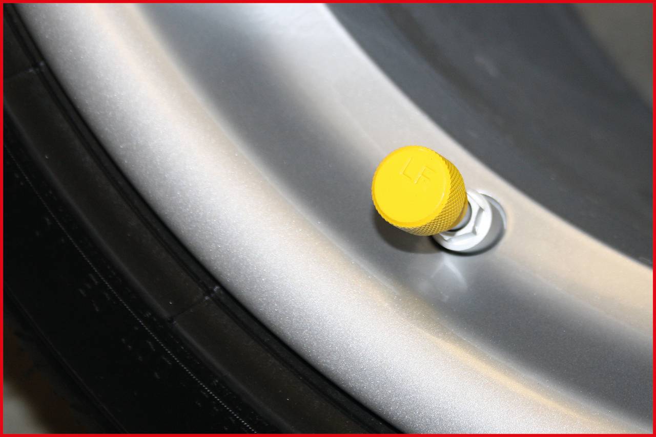 Tyre valve with a yellow cap, mounted on a silver wheel rim.
