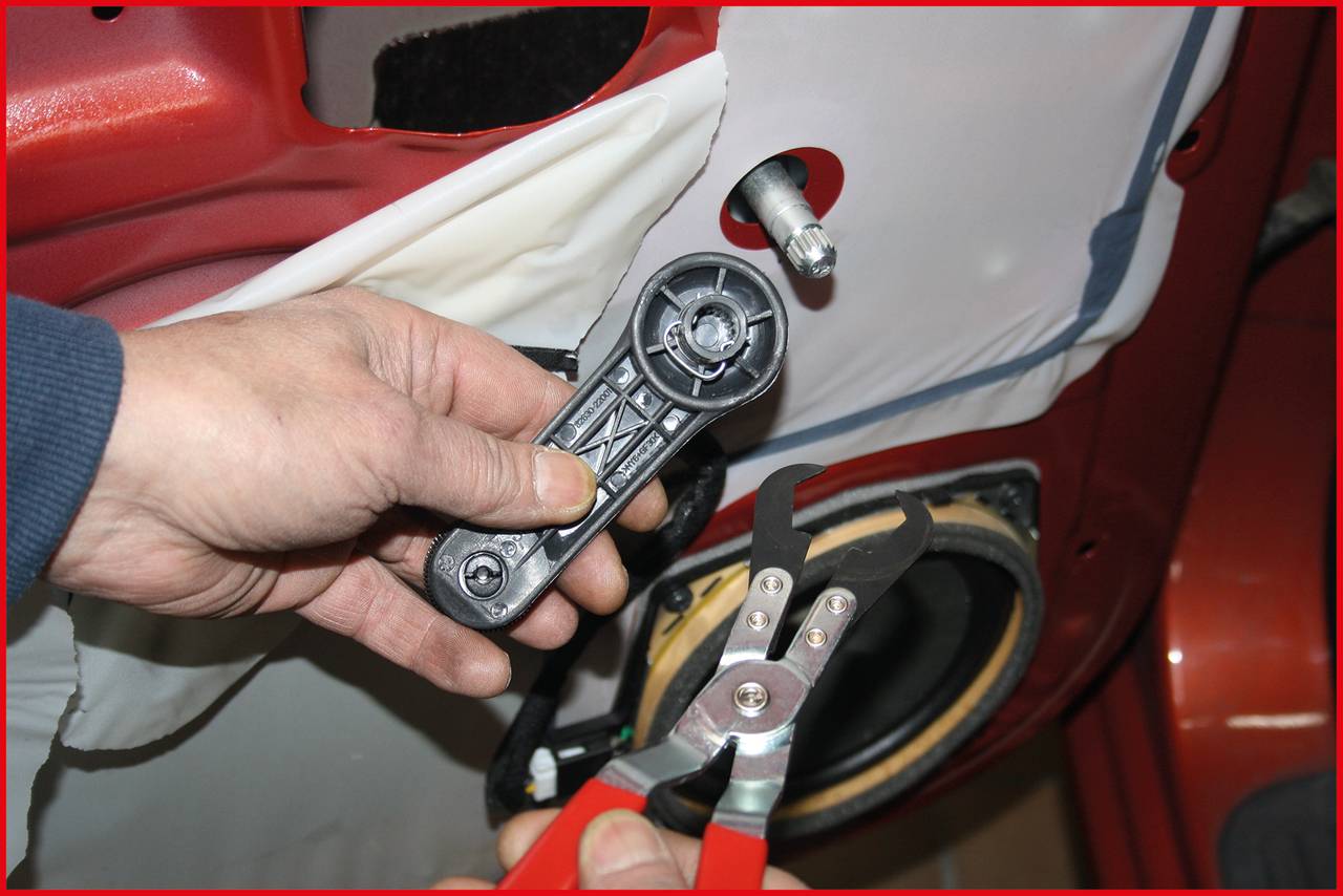 A person is holding a car door part and a specialised pair of pliers, apparently repairing a vehicle.