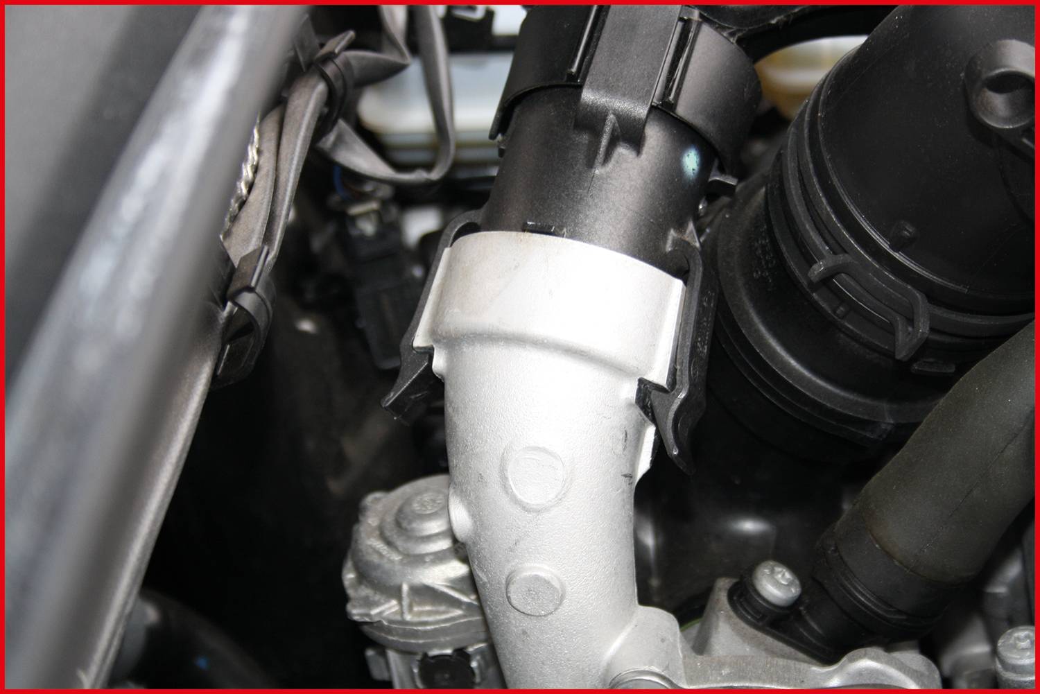 View of a car engine component with tubes and metal connections. Detailed close-up of technical components in the engine bay.