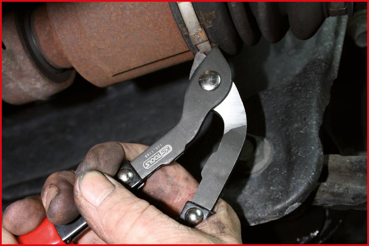 A person is using pliers to work on a vehicle part. Their hands are dirty, indicating mechanical labour.