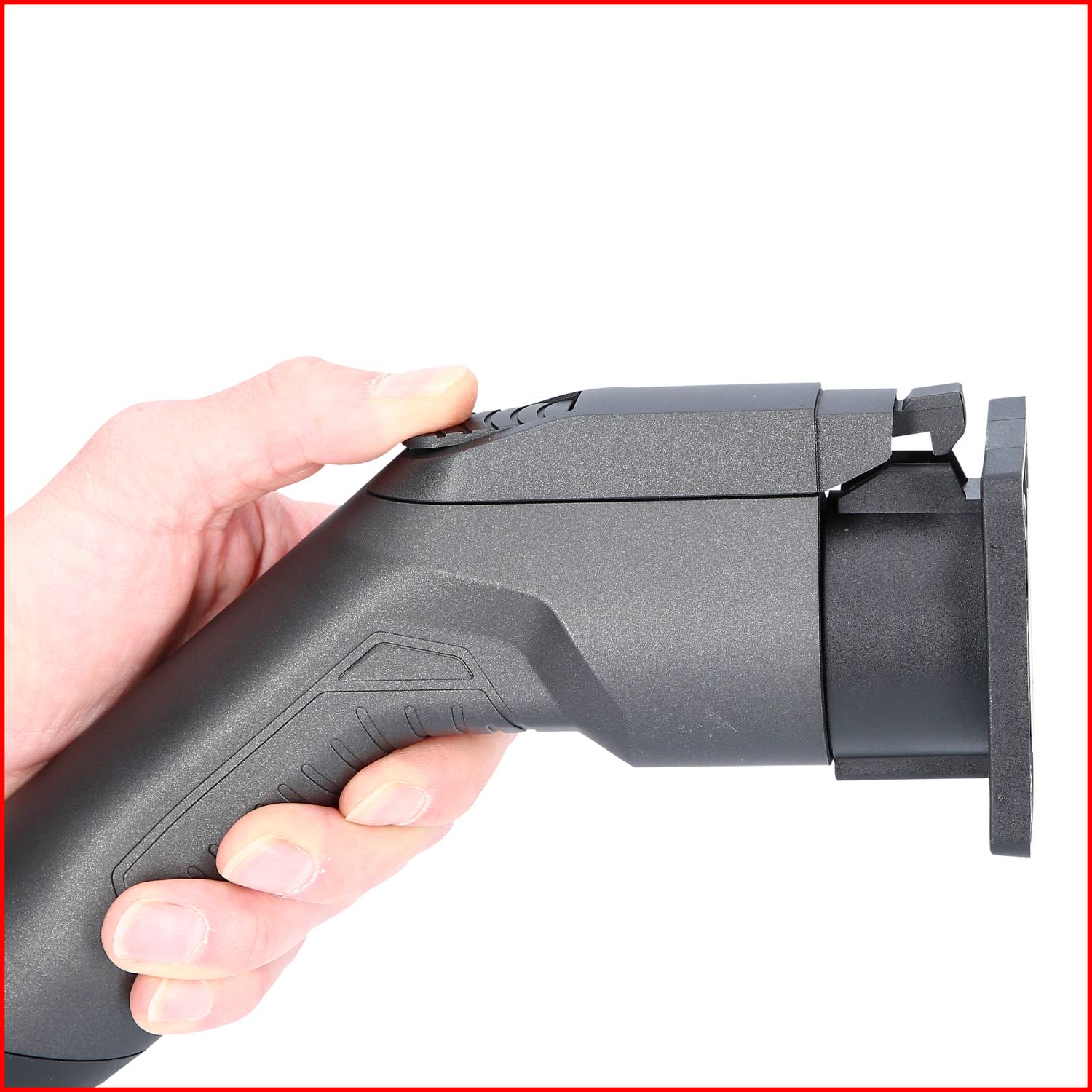 A hand holding an electric saw, side view. The saw is dark grey and is being held in the right hand.