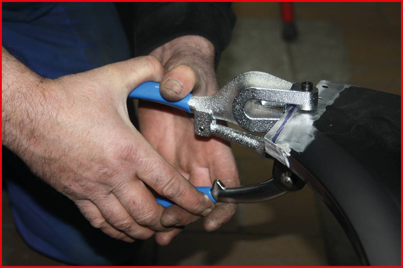 A man is using a metal pliers tool to bend a sheet of metal. Hands demonstrate a clear grip and tool precision.