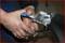 A man is using a metal pliers tool to bend a sheet of metal. Hands demonstrate a clear grip and tool precision.