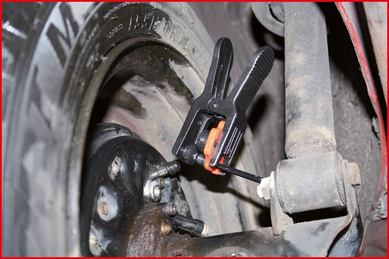 Close-up of a car tyre with a brake calliper attached to measure brake pad thickness. Tool emphasises maintenance.