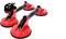 Two red suction lifters with black handles and a small black ratchet strap. Used for transporting or lifting smooth surfaces.
