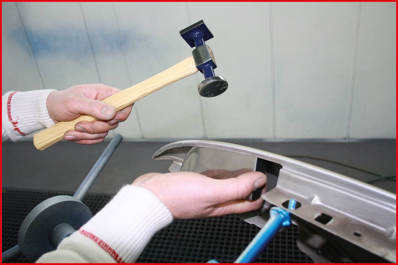 'A person is repairing a metal surface with a hammer.'