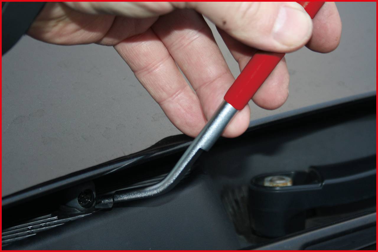 A hand pulls an object with a red pen from a black device or mechanism.