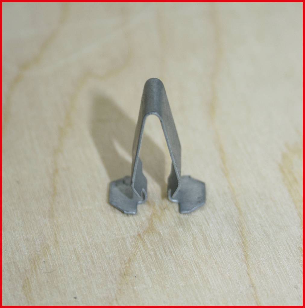Metal clip on wooden background, side view.