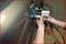 'A mechanic repairs a dent on a car door using a specialist tool.'