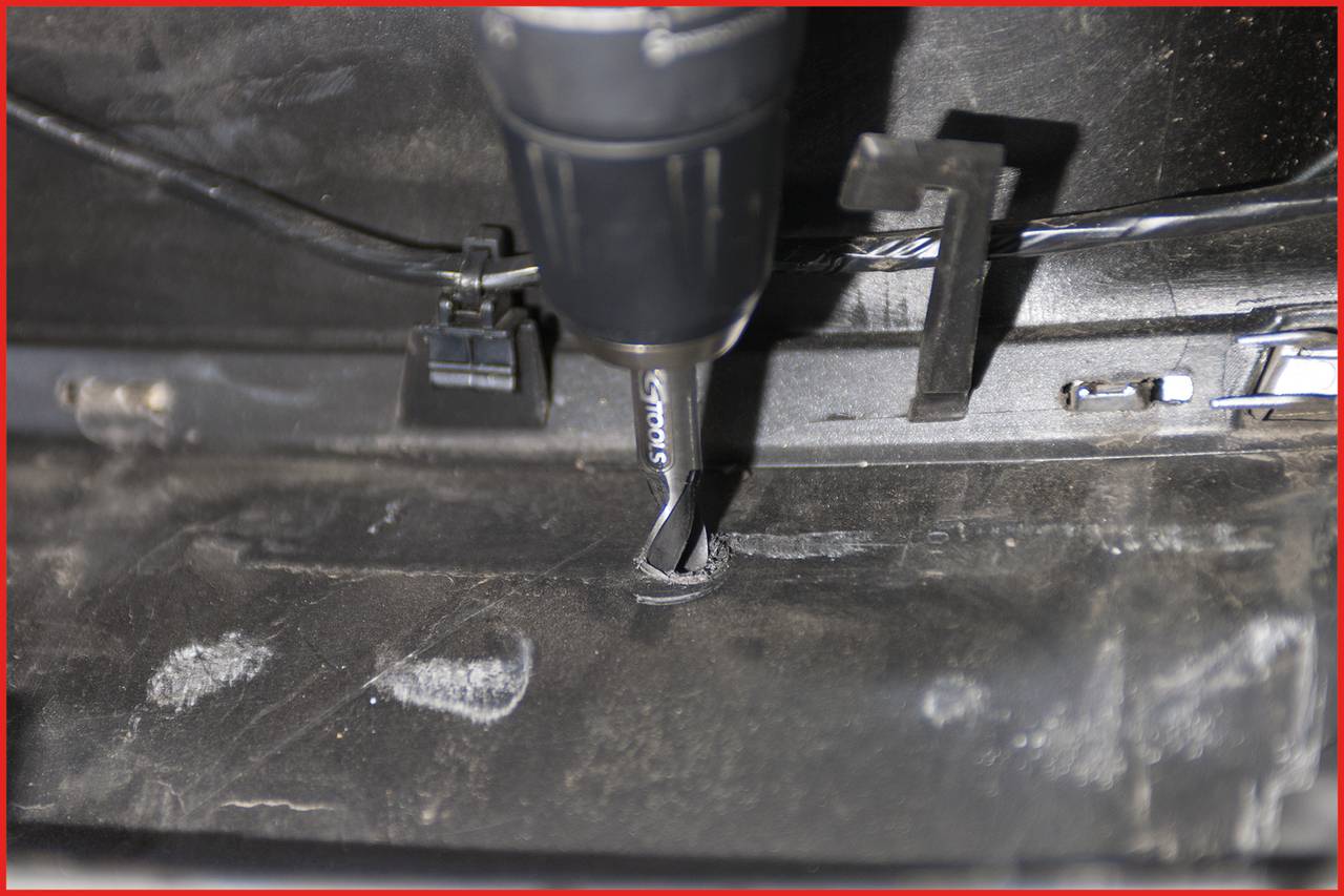 'Close-up of a drill boring a hole in a black material.'