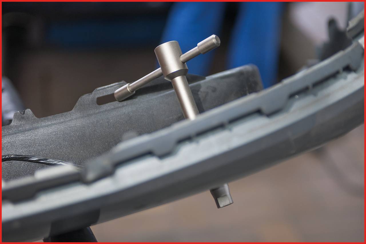 Tool being used to remove a bicycle tyre on a workbench. The tool is gripping the rim to release the tyre.