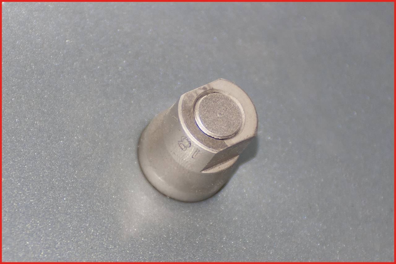A silver-coloured bolt protrudes from a smooth, grey surface. The bolt has a cylindrical shape.
