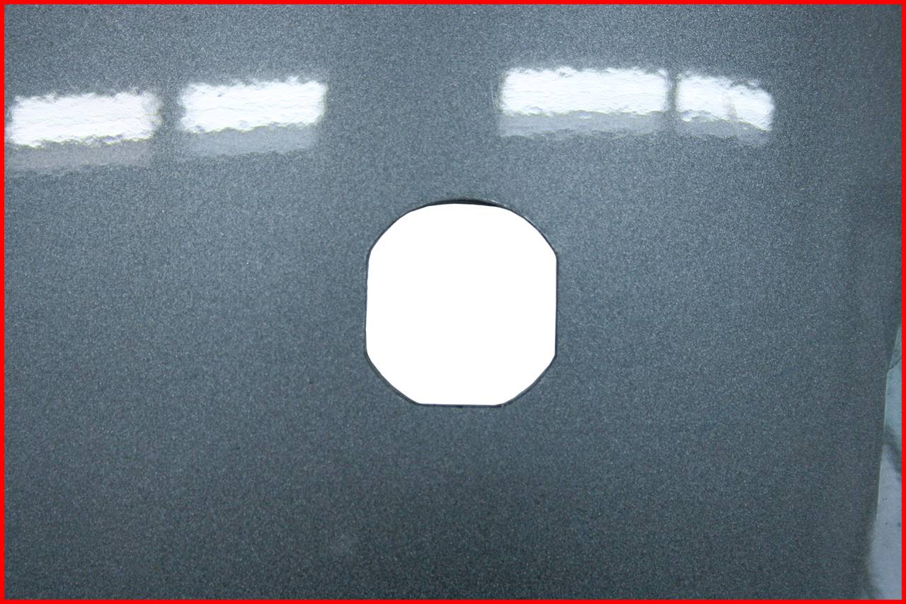 A hole in a grey metal sheet with a red frame. Reflected light visible on the surface.