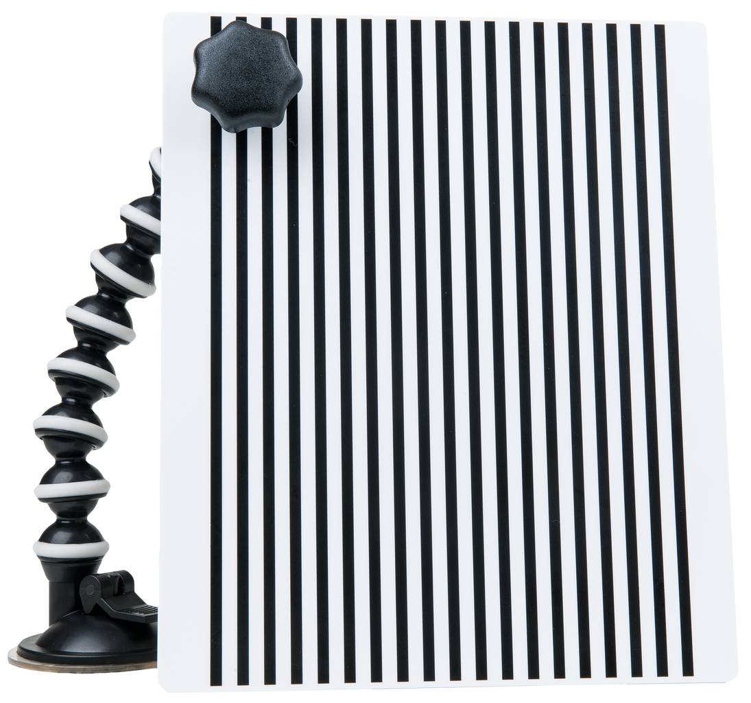 A flexible holder with a suction cup holds a plate with parallel black and white stripes.