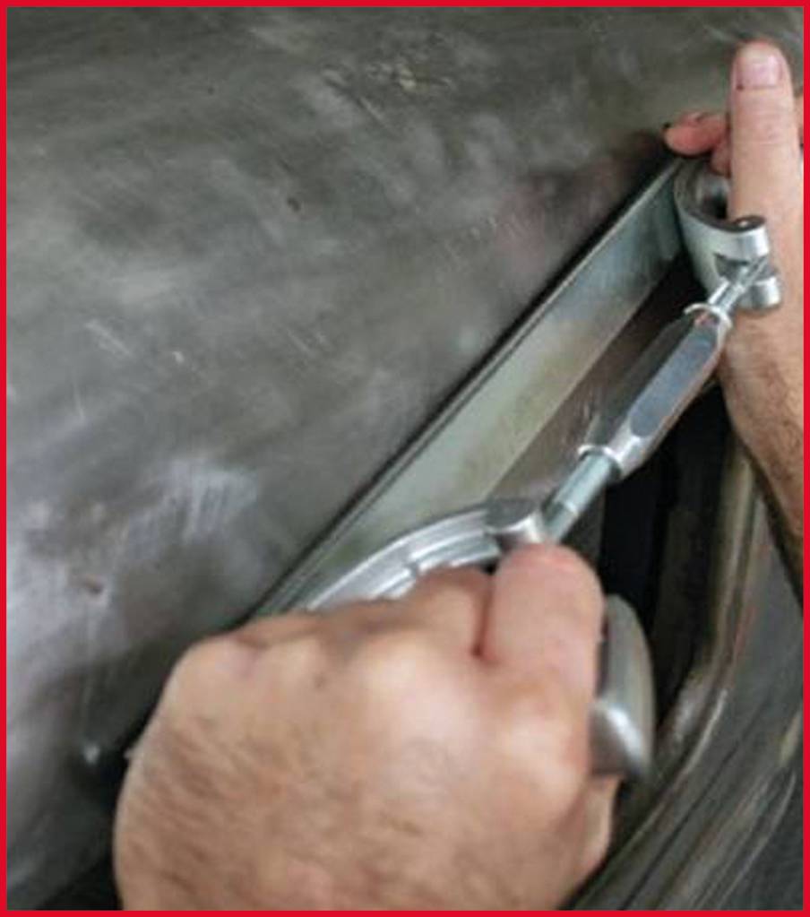 Two hands are working with a sheet metal tool on a metal surface.