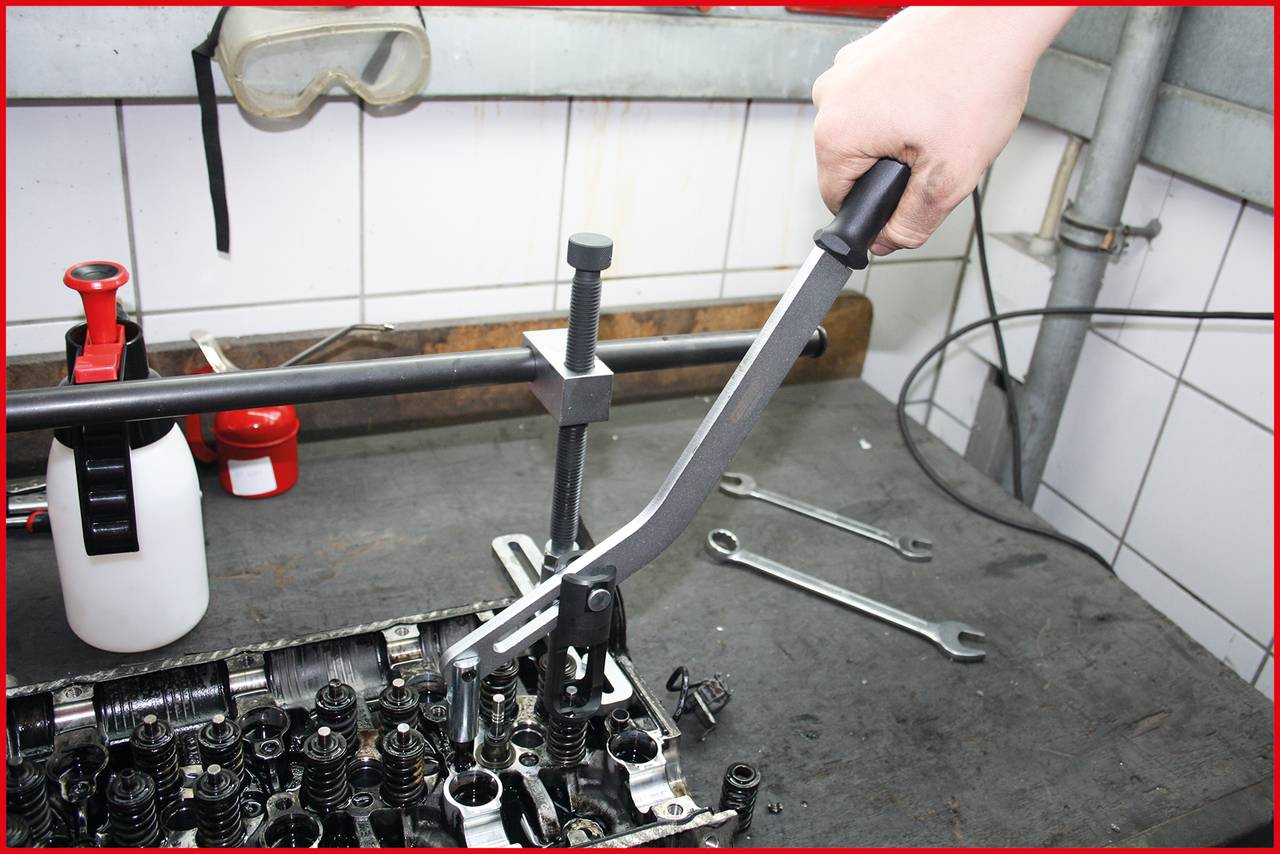 A person is repairing an engine in a workshop. Tools and engine components are spread out on the table.
