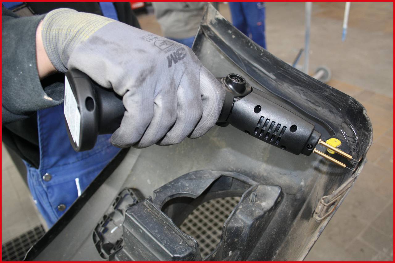 A person is grinding a grey plastic surface with an angle grinder, wearing protective gloves.