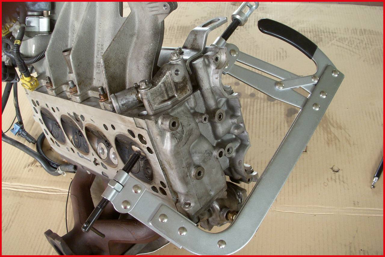 Motor assembly with mounting frame: An incomplete engine lies on a workbench, stabilised by a metal frame.