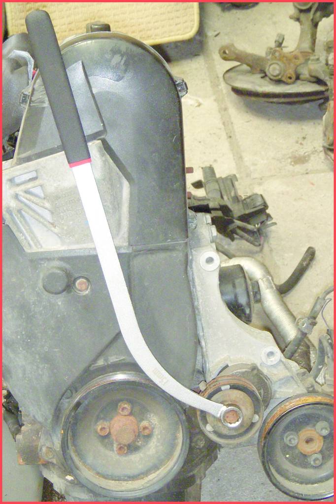A motor with covers and pulleys. A metal tool is attached to one of the pulleys to support repair work.