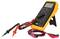 Digital multimeter with a yellow casing, black display, and red and black test leads. Standing vertically on a stand.