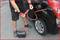 A person is siphoning petrol from a car using a red hose into a black jerry can.