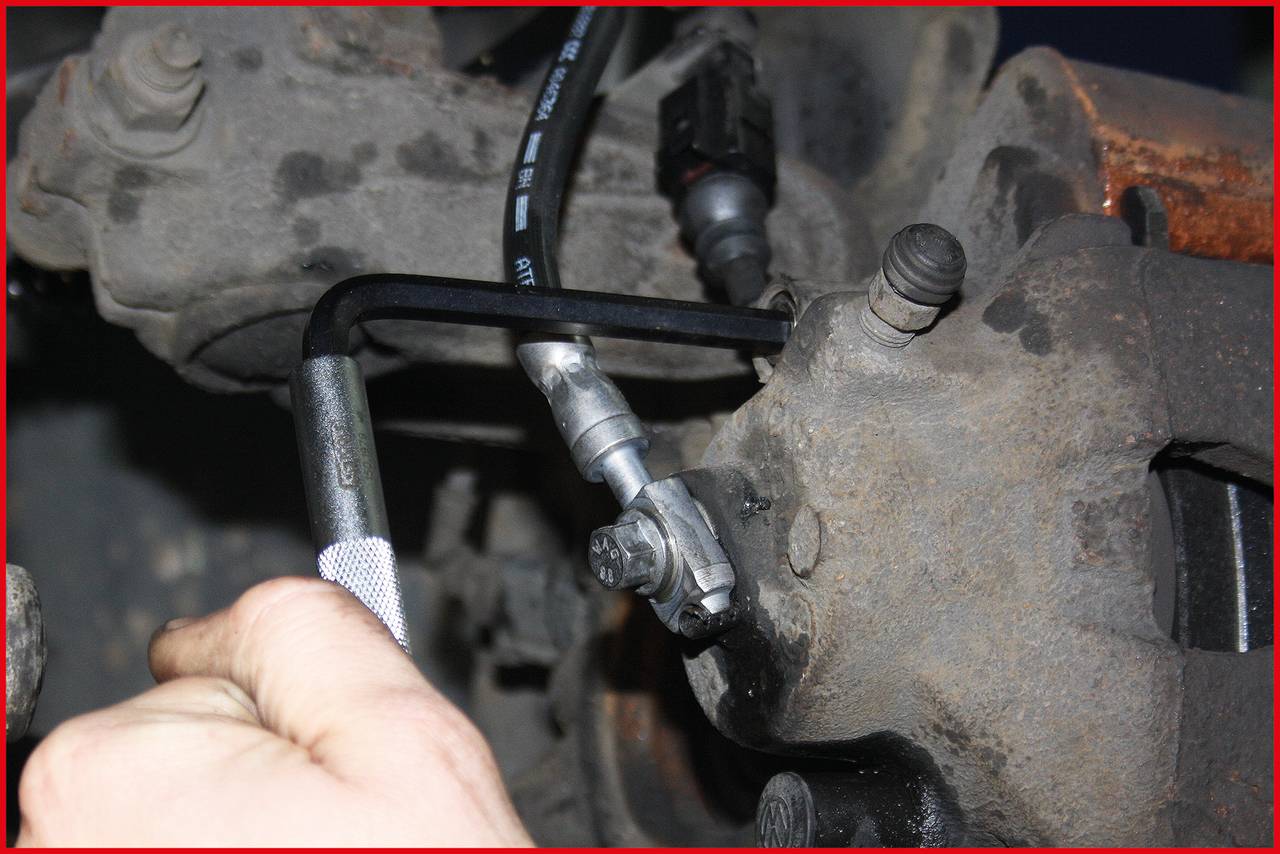 'Close-up of a car mechanic working on a brake with an Allen key. The focus is on the hand and the tool.'