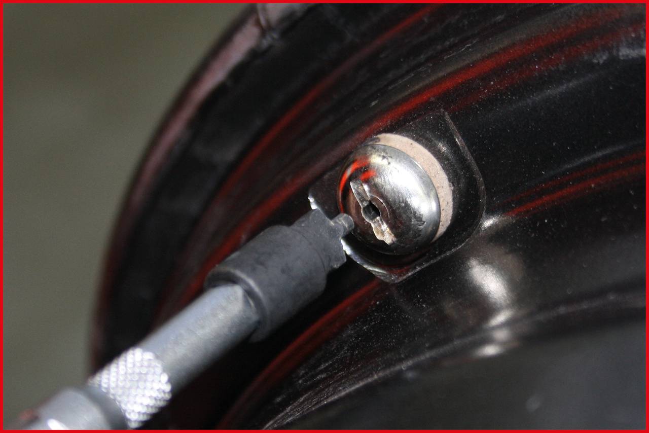 Close-up of a bicycle valve with a bicycle pump inserted.
