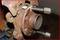 A rusty car part with two long bolts in a metal wheel bearing. The part is resting on a wooden surface.