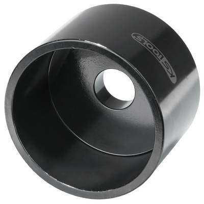 A black cylindrical metal tool with a hole in the centre, used for processing or adapting materials.