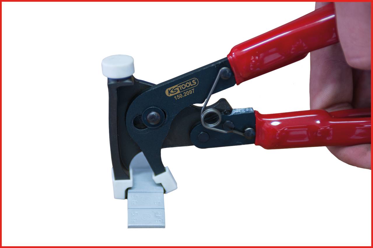 A hand is holding a special pliers with a red handle, gripping a metal piece. The tool is labelled 'KS TOOLS 150.2007'.