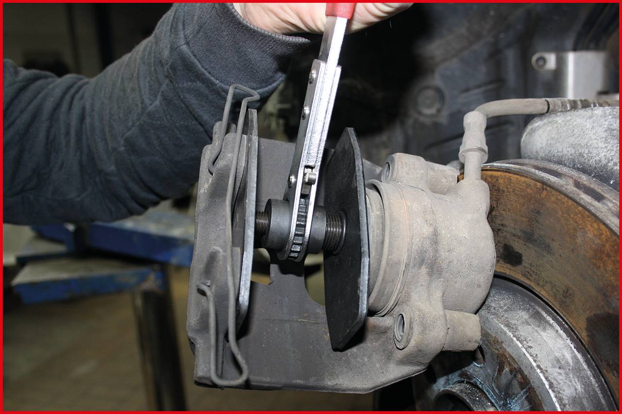 A person is measuring the thickness of a brake disc with a calliper to check its wear condition.