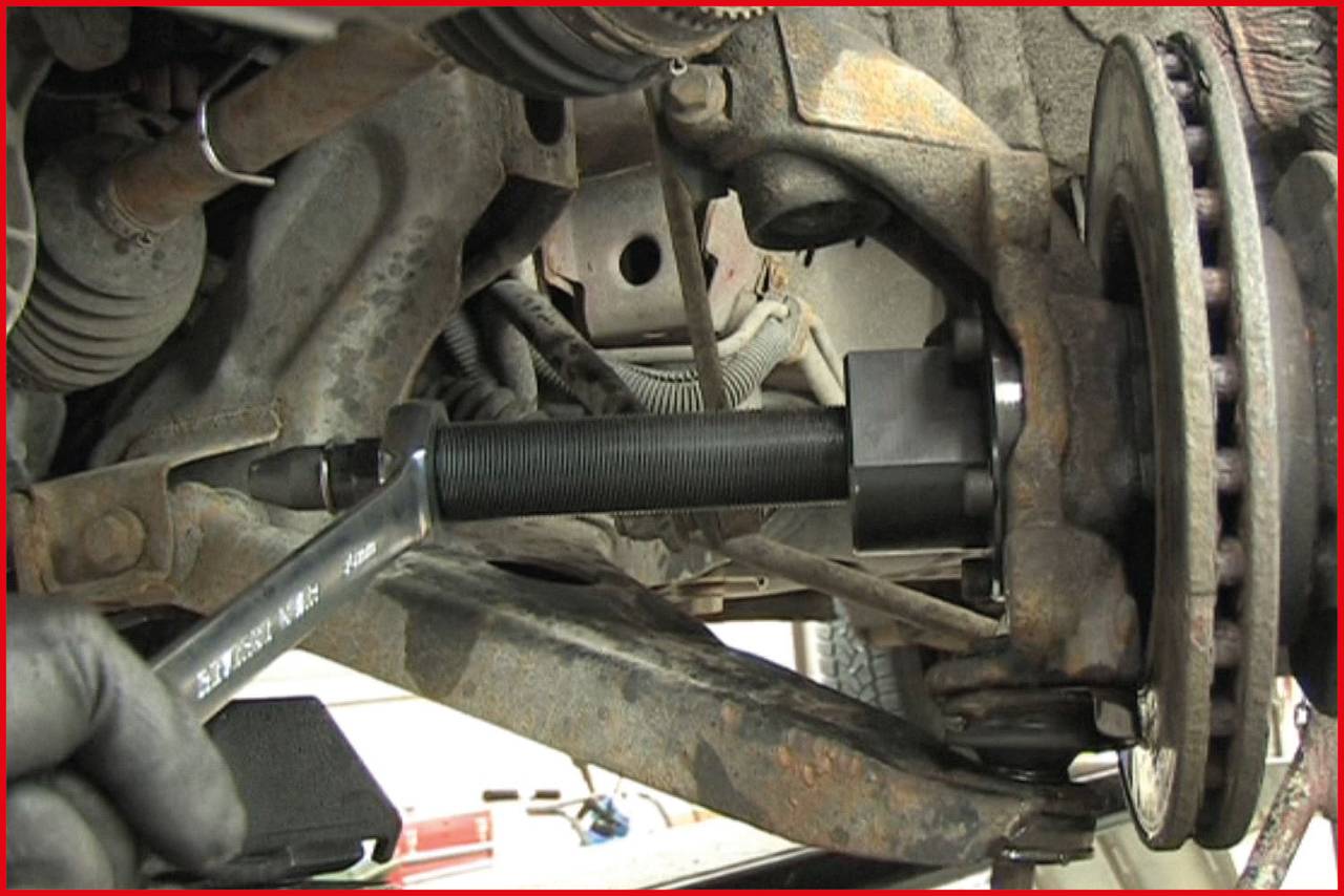 A close-up of an automotive part shows a repair with a specialised tool to remove or install a wheel bearing.