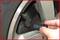 'Close-up of a hand placing a tyre pressure gauge against a car tyre valve to check the tyre pressure.'