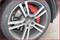 Close-up of a car tyre with a silver rim and a red brake calliper behind the rim. Brand logo visible in the centre.