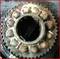Close-up of a rusted bearing with gear teeth, covered in dirt and oil. The bearing shows clear signs of wear.