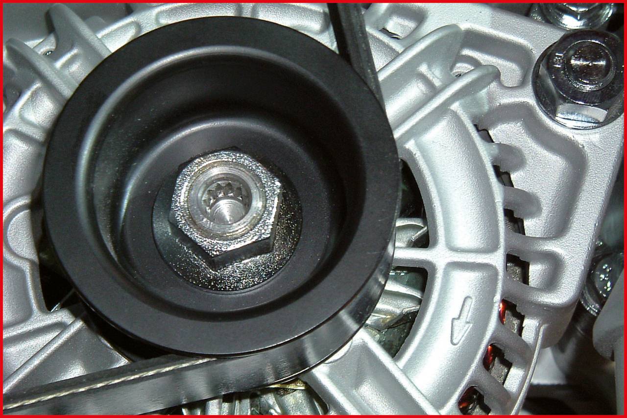 Close-up of an alternator with a belt. Clear view of the silver casing and a large screw in the centre.