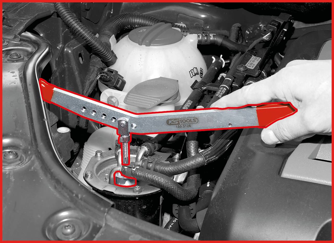 A person is pointing at a car part in the engine bay while using a tool. The tool is being used to loosen hose clamps.