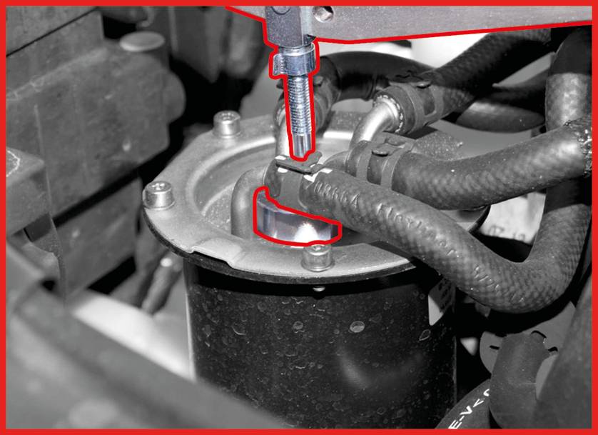 'Close-up of a mechanical component with two hoses and a screw fastened to a metal surface.'