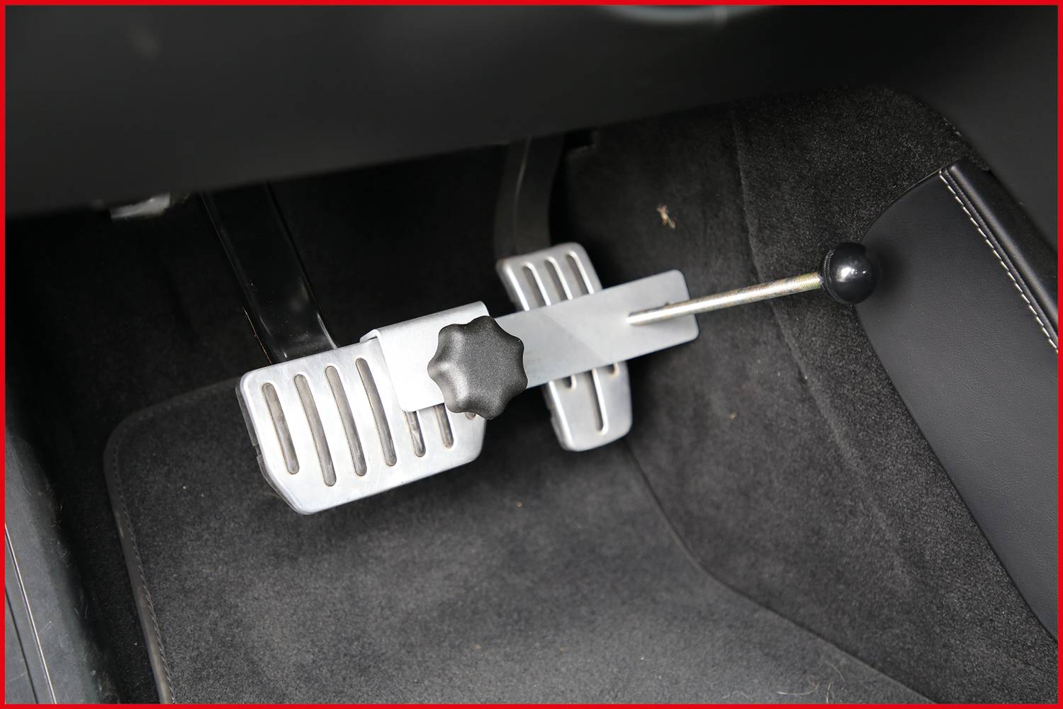 Vehicle pedal assembly within the interior, with an integrated hand-operated device attached to the accelerator pedal.