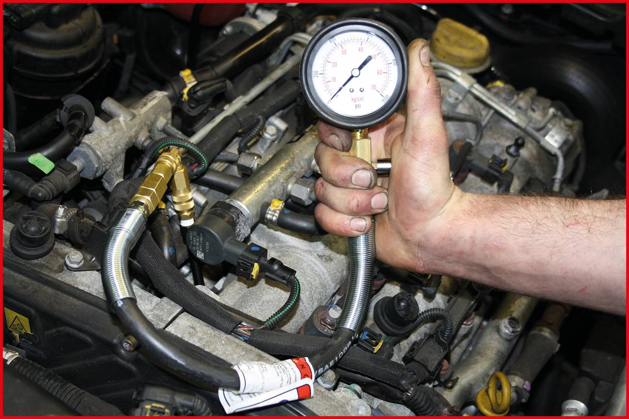 A person is measuring the pressure on a vehicle engine using a pressure gauge. Various hoses and components are visible.