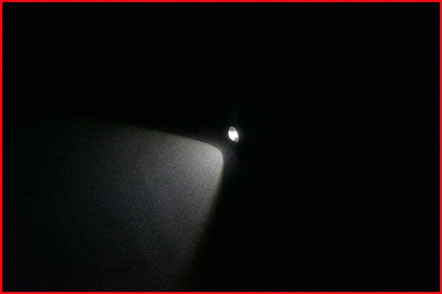A torch beams a cone of light in a dark room.