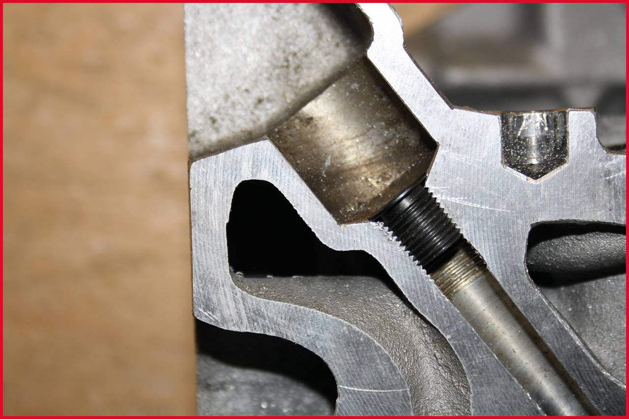 Close-up of a metal piece with a threaded bolt, showing mechanical components. The surface texture is clearly visible.