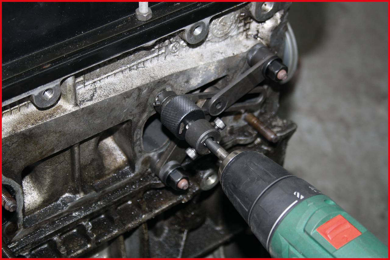 An electric spanner is used to loosen a screw on a heavily soiled machine component.