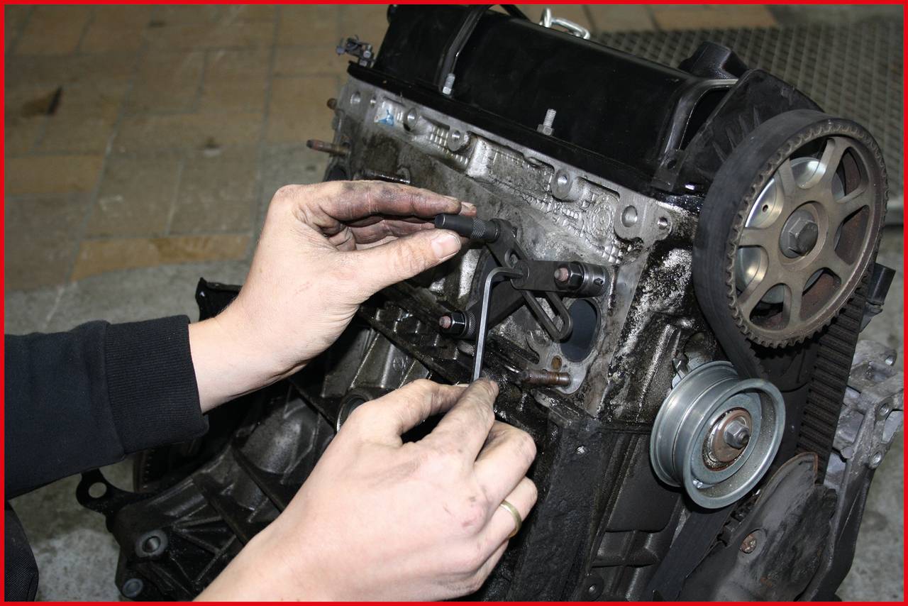 A person is repairing an engine with an Allen key, surrounded by engine components. The scene depicts a technical work process.